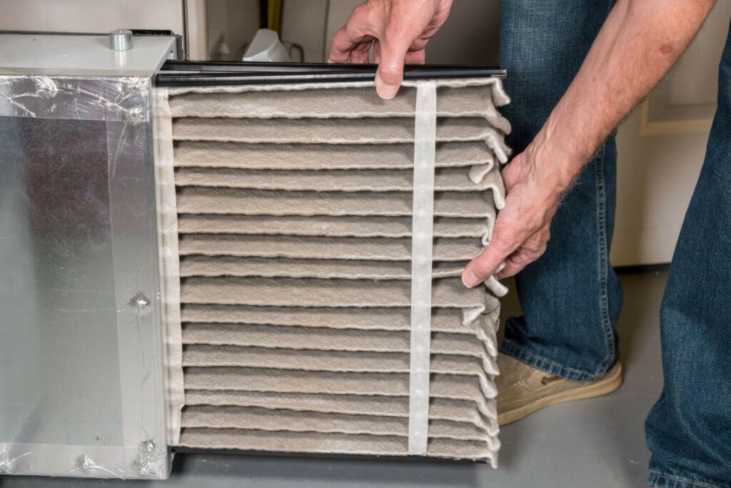 technician removing a dirty pleated air filter